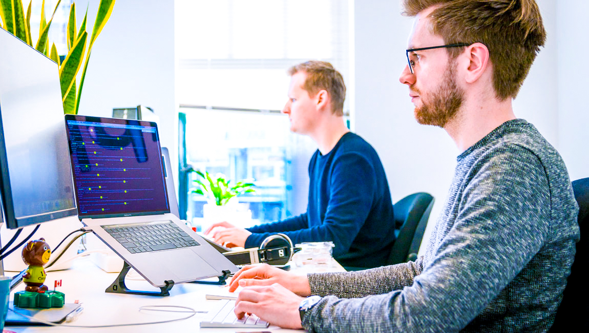 Two businessmen using computers at their desks