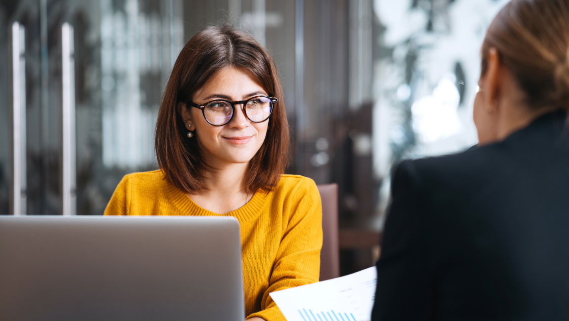 Smiling businesswoman at desk talking with someone else