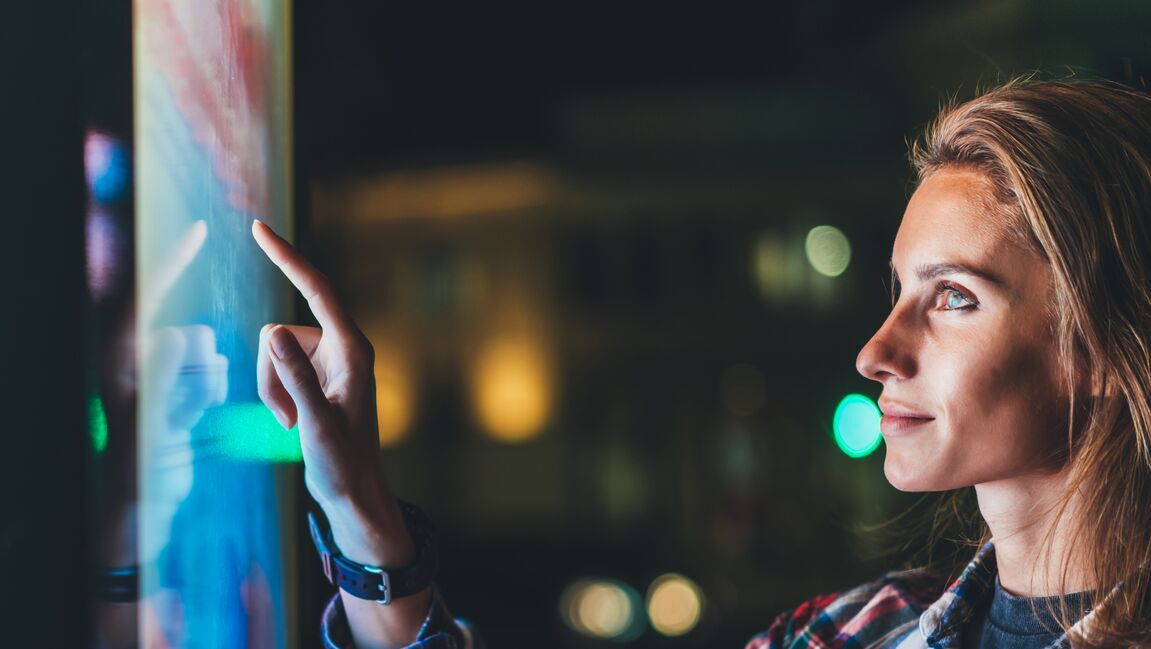 Woman pointing at smart screen at night