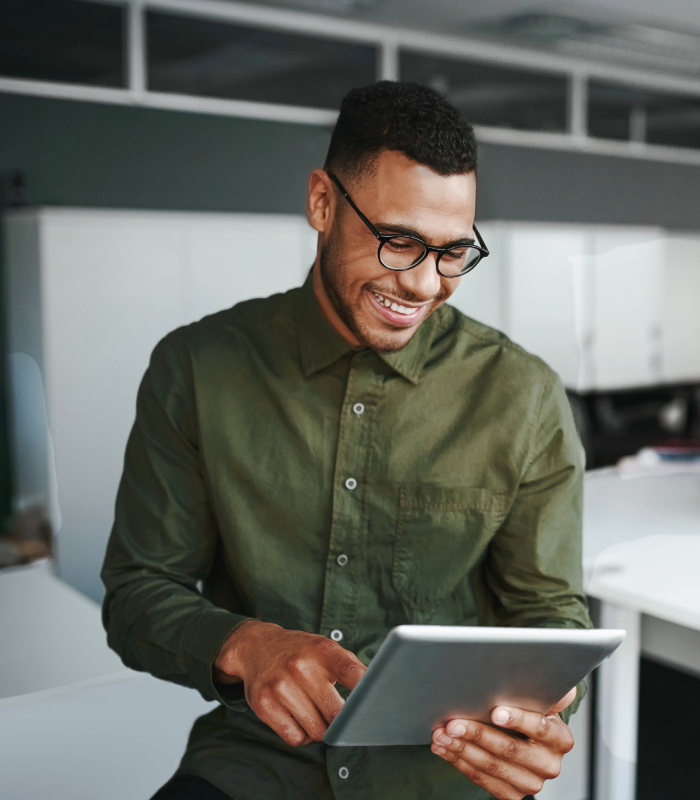 Smiling businessman wearing olive colored shirt looking at tablet